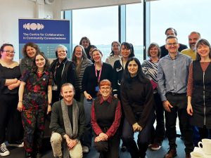 A group of people stand smiling at the camera, with a banner in the background that has the Centre logo on it.