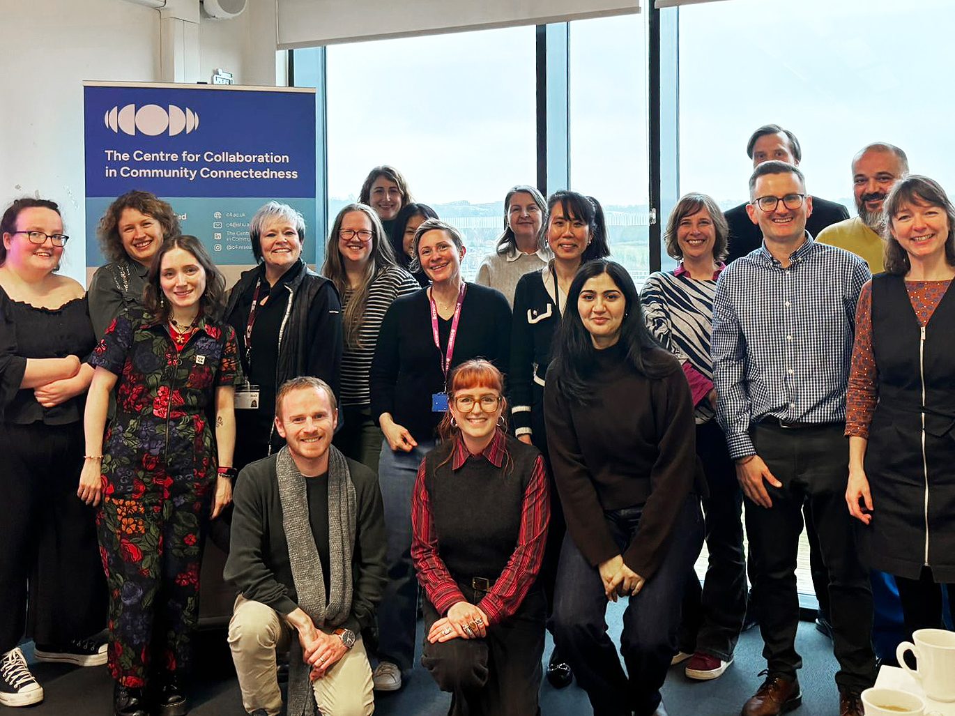 A group of people stand smiling at the camera, with a banner in the background that has the Centre logo on it.