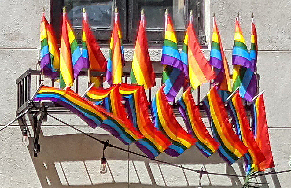 A lot of pride flags hanging from a balcony.