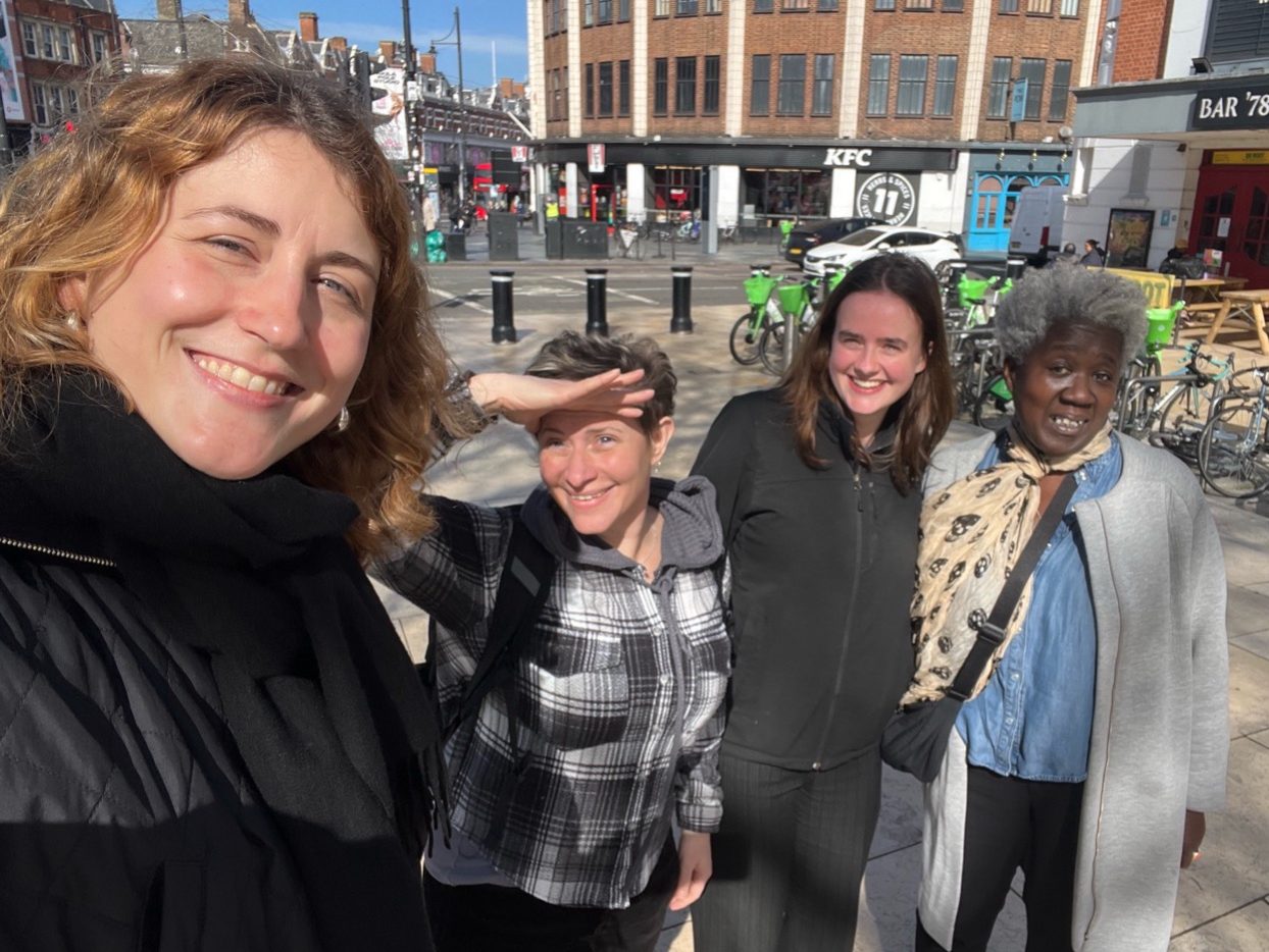 Franca Roeschert along with Nic Dickson, Binki Taylor and Catriona Macleod out on a walk around Brixton. Franca is smiling whilst holding the camera. The other team members are also smiling. It is a bright and sunny day.