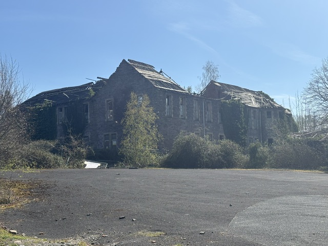 A large derelict building missing portions of the roof structure.