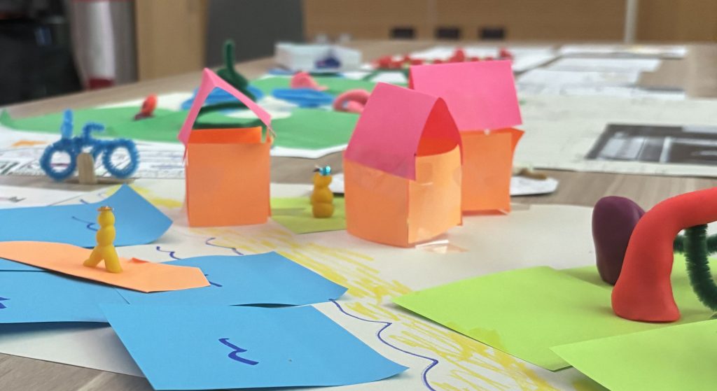 Paper models of house-like structures on a beach.